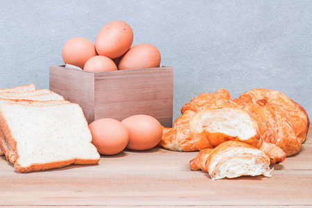 Croissant Bread and eggs in a wooden box on a wooden table in the kitchen. Breakfast concept.