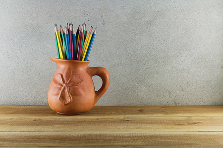 Pencil in a earthenware cup on a wooden table.の写真素材