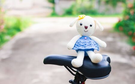 Knitted dolls on black bicycle saddle with soft focus and blur background. Concept travel.の写真素材