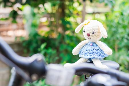Knitted dolls on black bicycle saddle with soft focus and blur background. Concept travel.の写真素材