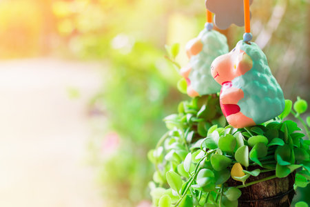 Dolly the sheep red heart with smile of love, ornamental plants, hanging green on light bokeh background and with ray of light yellowの写真素材