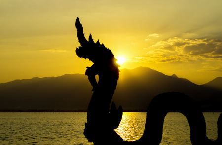 Black naga silhouette with backdrop is lake where the sunset.の写真素材