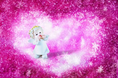 Little angel on winter background of pink sky with snow. For Christmas, New Year and love in Valentine's Day. With copy space.の写真素材