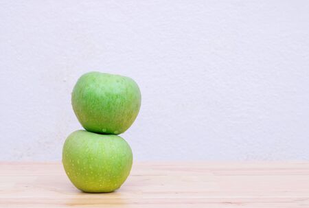 Two green apples on wooden table with concrete walls white background. And have copy spaceの写真素材