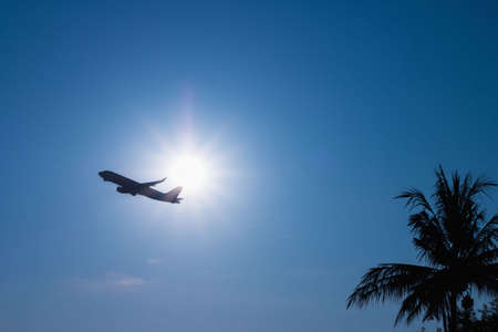 Commercial airplane flying above clouds through the sunlight and beautiful blue sky.の写真素材