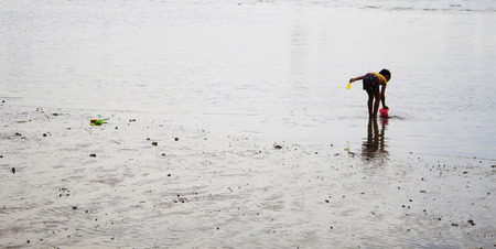 Beautiful girl playing sand in the evening riverの写真素材
