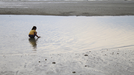 Beautiful girl playing sand in the evening riverの写真素材