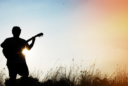 Abstract beautiful man playing Guitar in the foreground on sky background.の写真素材