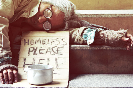 Could you please help homeless man sleeping on walkway street in the capticap city.の写真素材
