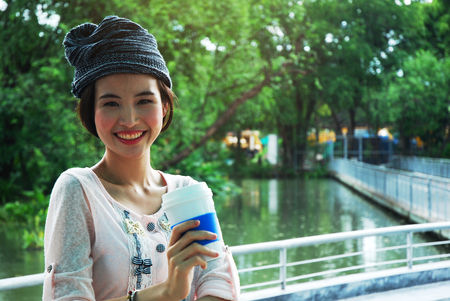 Beautiful girl teen standing and holding coffee cup in the public park.の写真素材