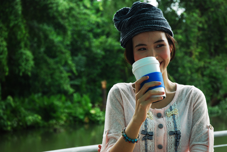 Beautiful girl teen standing and holding coffee cup in the public park.の写真素材
