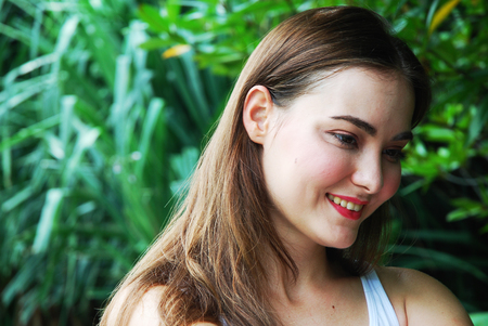 Beautiful woman face portrait close up with blurred tree background in the public park.の写真素材