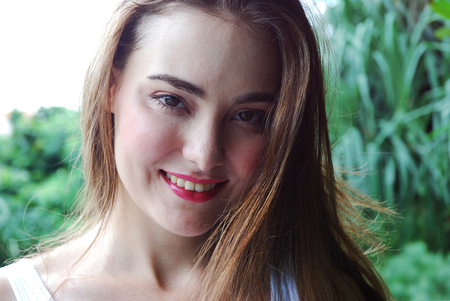 Beautiful woman face portrait close up with blurred tree background in the public park.の写真素材
