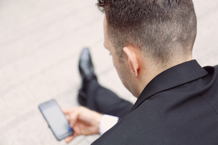 Business man looking on mobile phone on street and blur mobile phone device.の写真素材