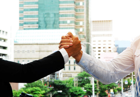 Business man handshake and offices building background.