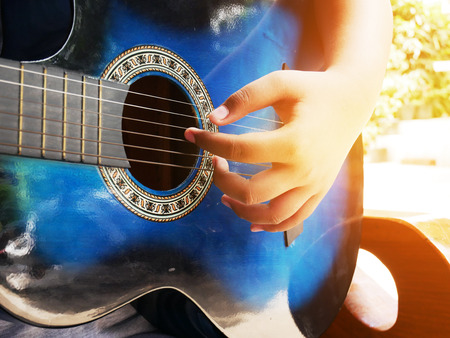 Close-up hand playing acoustic guitar and sitting in indoor.の写真素材
