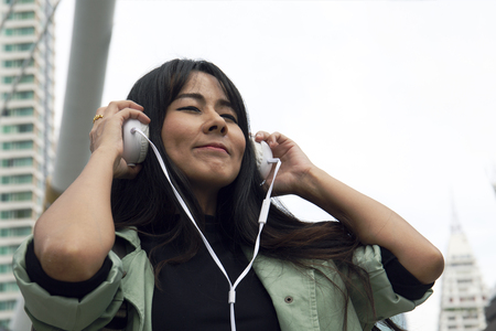 Close up beautiful woman listening music and offices building background.の写真素材