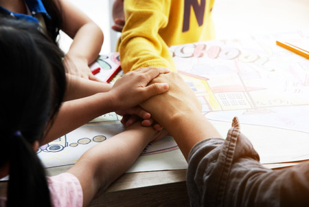 Teachers are teaching drawing on white paper to three children in holiday weekend. Background blurの写真素材