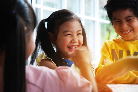 Teachers are teaching drawing on white paper to three children in holiday weekend. Background blurの写真素材
