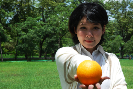 Beautiful girl teen smile and holding orange fruit in the Orange Garden.の写真素材