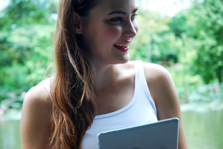 Beautiful girl traveling and holding smart tablet device in the public park.の写真素材