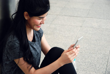 Beautiful Sport woman smile portrait and looking mobile phone device on walking street.