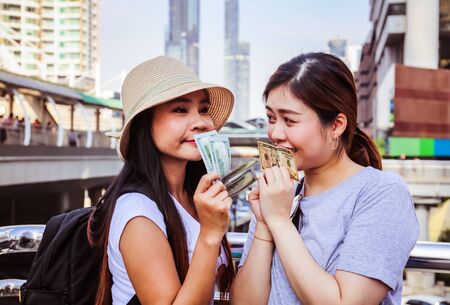 Beautiful two woman happy holding money for traveling in the city.の写真素材
