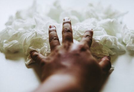 Close-up hand holding white paper tissue background.の写真素材