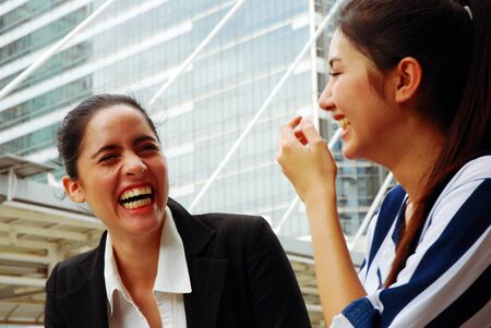 Both women are looking and talking friend close up on street in the city.の写真素材
