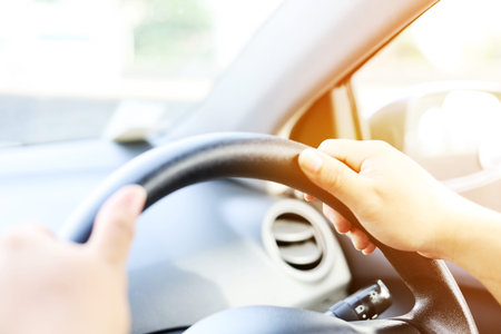 Close-up Hand holding the steering wheel of the car while driving.