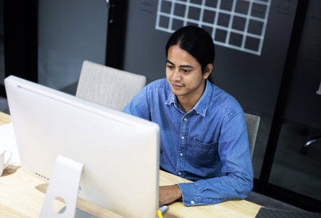 Close up Asian business man sitting and working on workstation at desk.