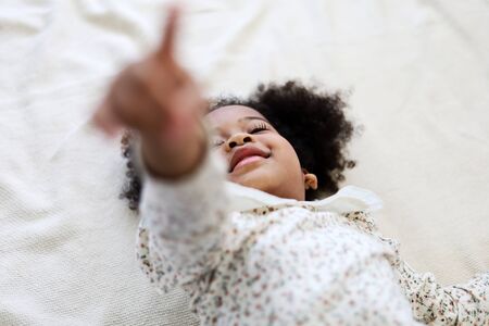 Beautiful African american girl kid smile portrait in bedroom at home.の写真素材