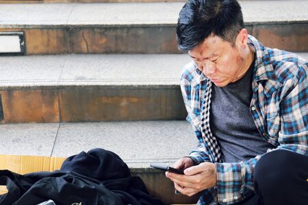 Senior homeless man sitting and ralaxation lifestyle on walking street.の写真素材