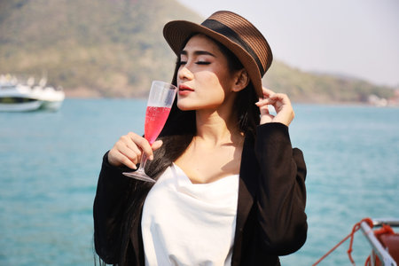 Beautiful Asia woman smile portrait traveling and drinking wine on speed boat in summer for relaxation at Thailand.の写真素材
