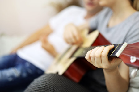 Young couple lover playing acoustic guitar on bedroom at home.