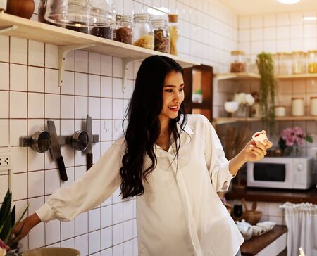 Beautiful Asia young woman smile portrait and cooking food in home.の写真素材