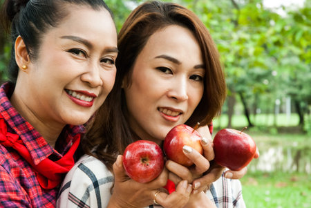 Beautiful family woman smile holding and eating apples at park.の写真素材