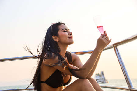 Beautiful young woman smile portrait traveling and drinking wine at speed boat in summer at ocean.の写真素材