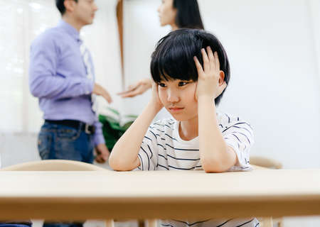 Unhappy family problems concept, father and mother quarreling in the house so causing children to feel bad.の写真素材