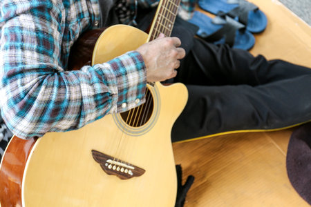 Senoir homeless man sitting and playing acoustic guitar.
