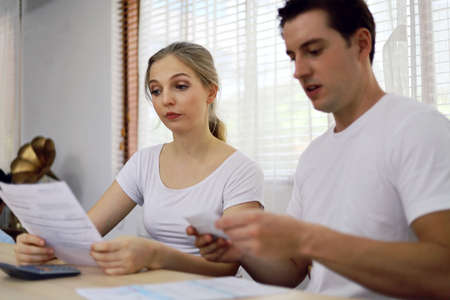 Unhappy young couple feeling worried about the cost for credit card bills at home.の写真素材