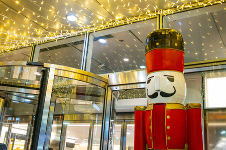 Giant red nutcracker holiday decoration under illuminated ceiling in luxury mall entrance, festive retail displayの写真素材