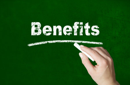 Person writing a Benefits word with chalk on a classroom style blackboardの写真素材