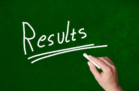 Person writing a Results word with chalk on a classroom style blackboardの写真素材