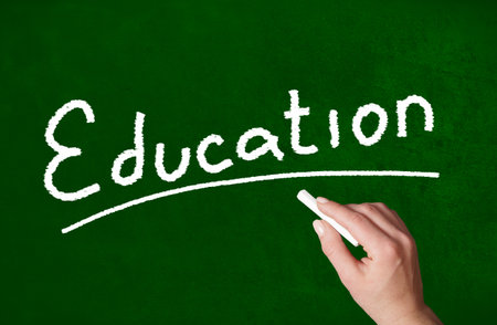 Person writing a Education word with chalk on a classroom style blackboardの写真素材