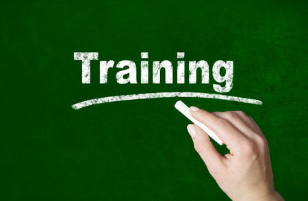 Person writing a word with chalk on a classroom style blackboardの写真素材