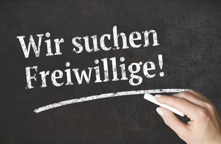 "We are looking for volunteers!" german word written in chalk on a blackboardの写真素材