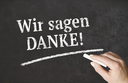 "We say thank you!" german word written in chalk on a blackboardの写真素材