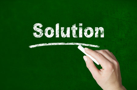 Person writing a Solution word with chalk on a classroom style blackboardの写真素材