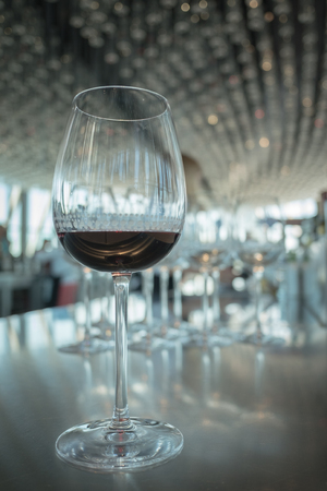 Wine glass with red wine on white bokeh background at luxury restaurantの写真素材
